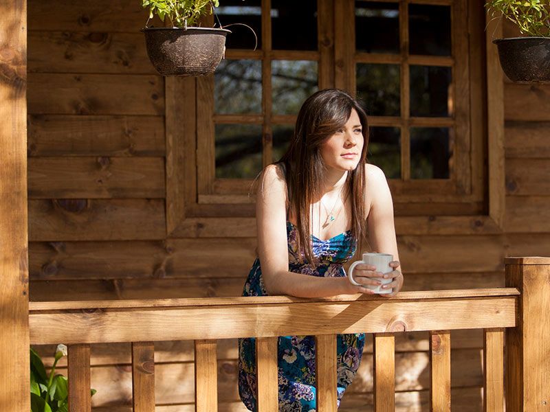 A woman enjoys coffee on a wooden porch in Newark, DE