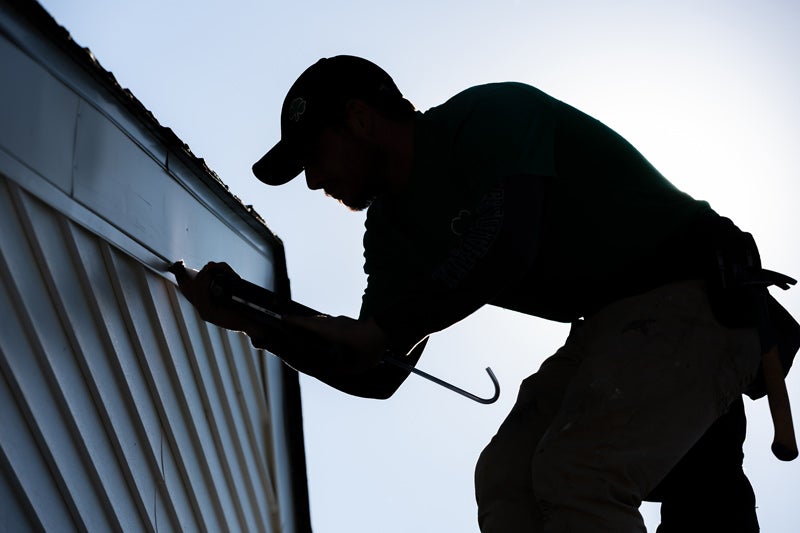 Person working on the siding of a house.