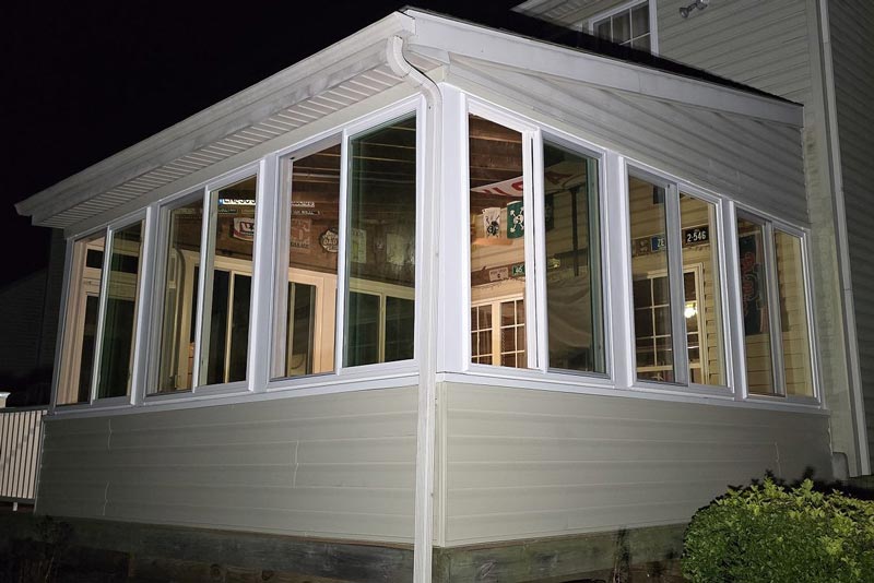 Exterior view of a sunroom with large windows at night