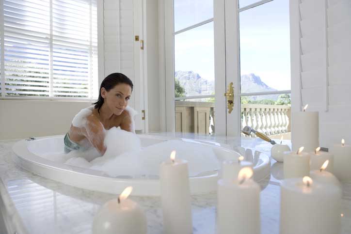 Young woman in bubble bath, portrait, illuminated candles in for